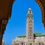 Framed-view-of-the-Hassan-II-Mosque-minaret-through-an-ornate-archway-in-Casablanca-with-clear-sky