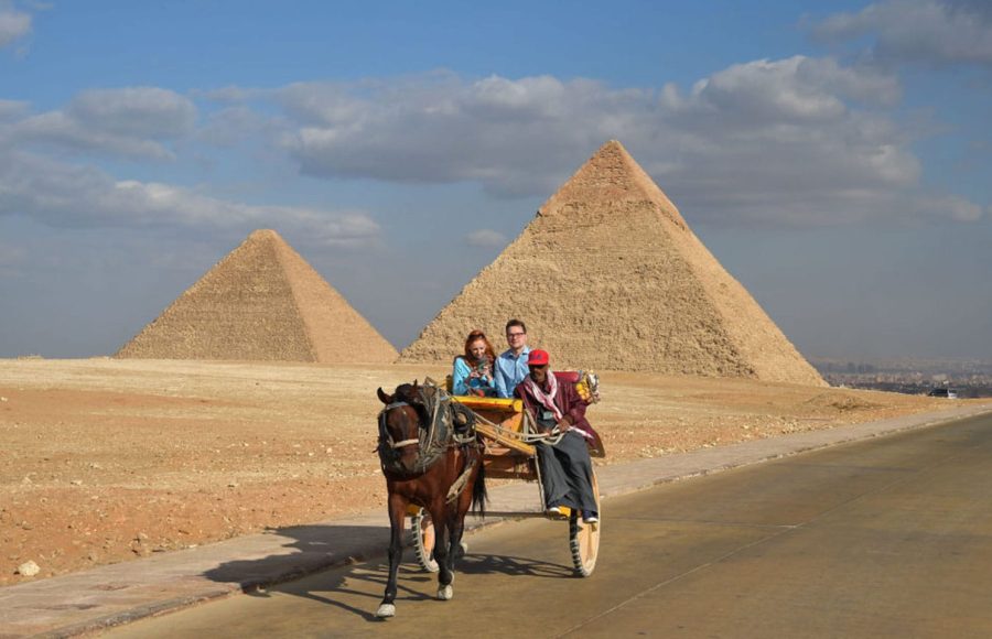 Travelers enjoying a scenic pyramids & Sphinx excursion in a traditional horse carriage