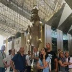 A group of travelers looking up at a colossal statue of Ramses II during their Trip to Grand Egyptian Museum