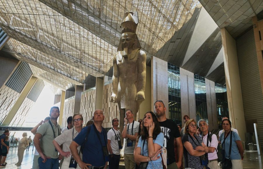 A group of travelers looking up at a colossal statue of Ramses II during their Trip to Grand Egyptian Museum