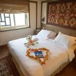 Double bed decorated with towel swans and a golden heart