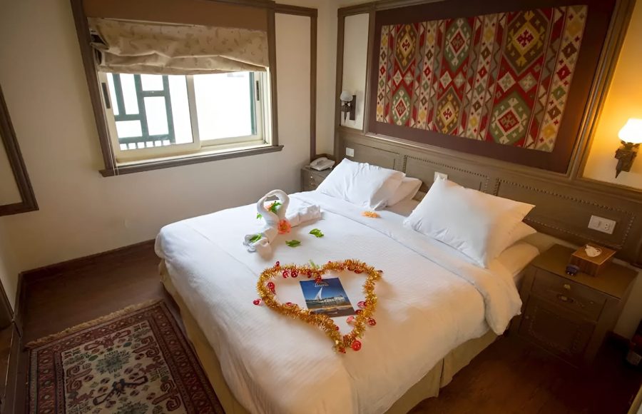 Double bed decorated with towel swans and a golden heart