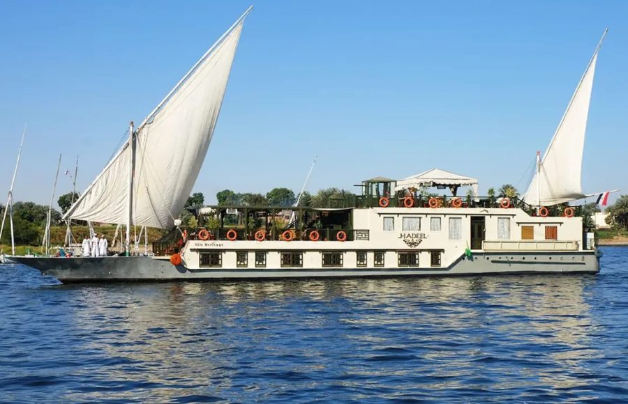 A white and gold Dahabiya sailing boat with two large sails on the Nile.