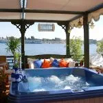 Blue outdoor hot tub on a boat deck overlooking the river.