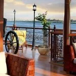 Open-air lounge with woven sofas and vintage-style lampposts at sunset.