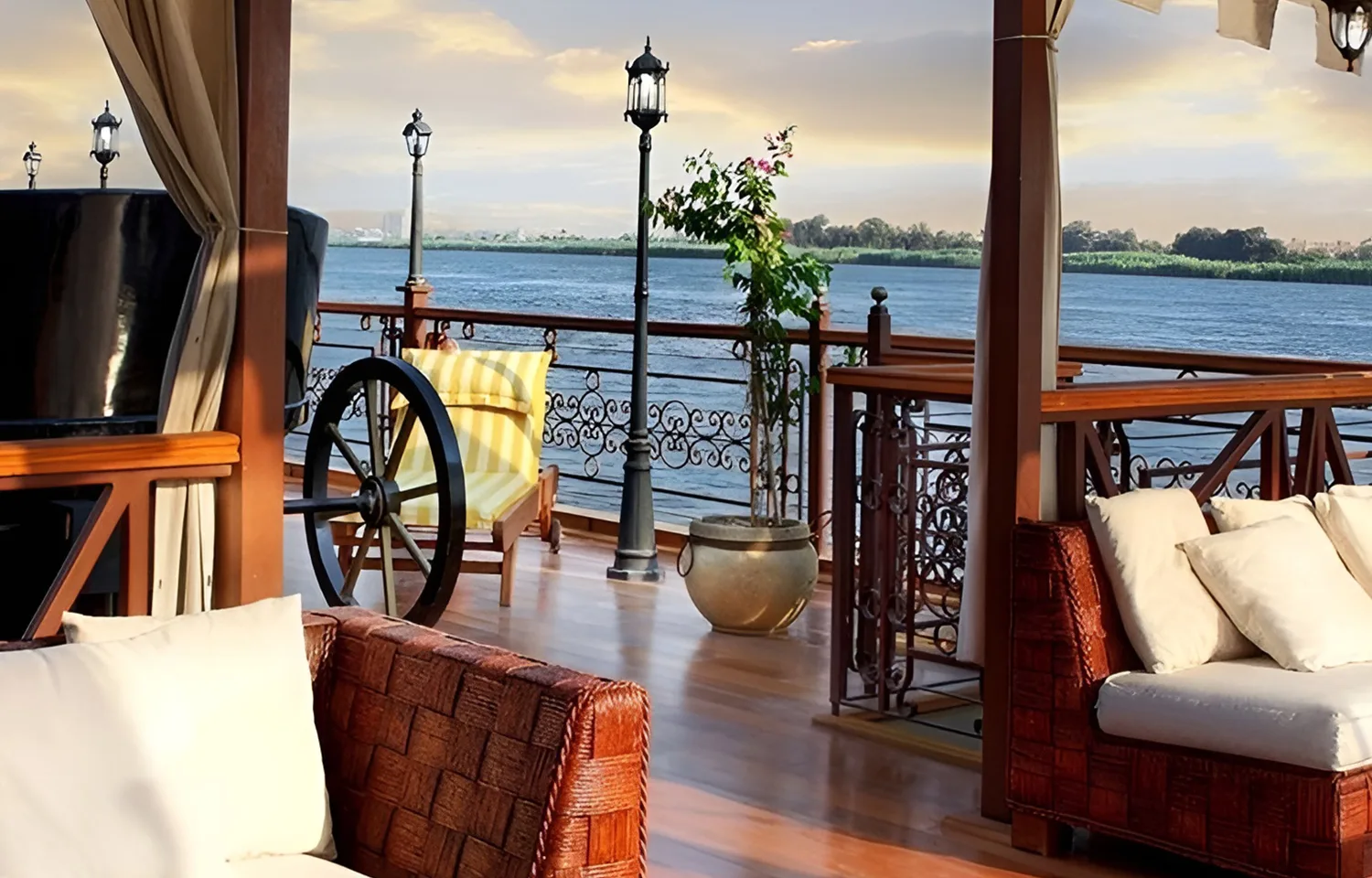 Open-air lounge with woven sofas and vintage-style lampposts at sunset.