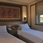 Two twin beds in a wood-paneled cabin with Egyptian wall art.