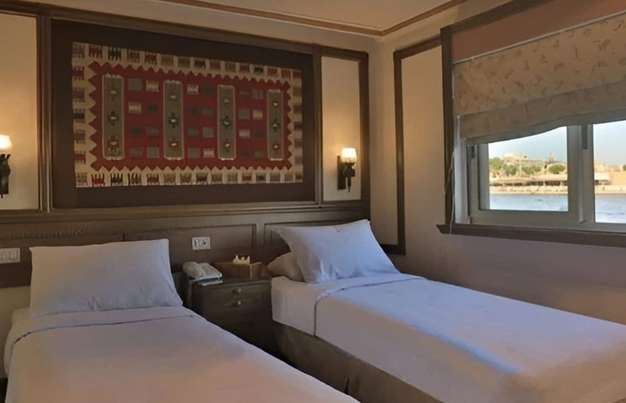 Two twin beds in a wood-paneled cabin with Egyptian wall art.