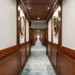 Long, elegant cabin hallway with wood paneling and framed mirrors.