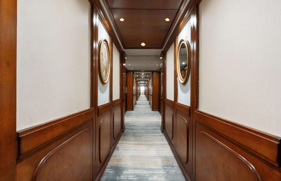 Long, elegant cabin hallway with wood paneling and framed mirrors.