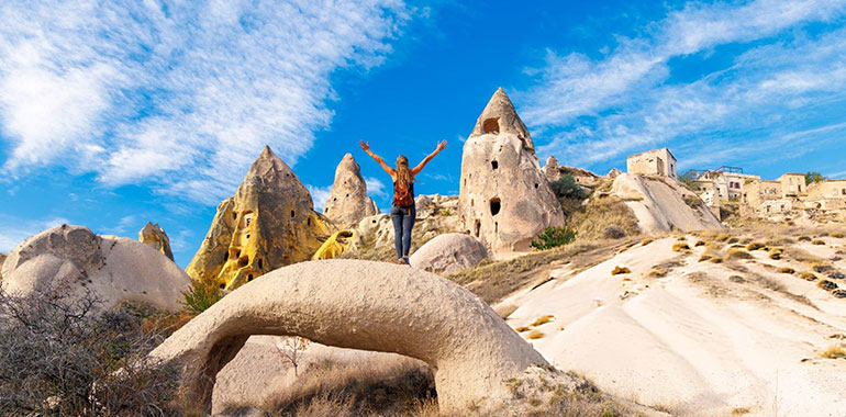 Happy Traveler Standing on Rock with Arms Raised Overlooking Fairy Chimneys in Cappadocia Turkey
