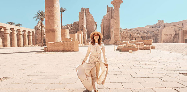Happy Woman Traveler Explores The Ruins Of The Ancient Karnak Temple In The Heritage City Of Luxor In Egypt