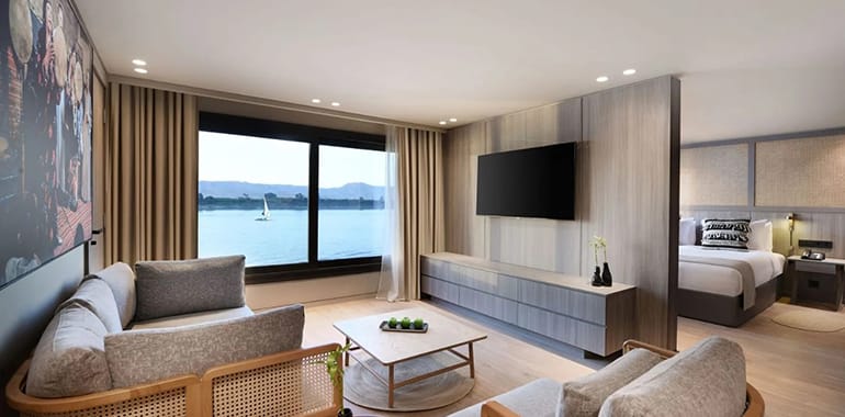 Interior Of A Luxury Nile Cruise Cabin With River-View Window, Modern Amenities, And Elegant Dining Area Onboard.