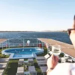 A woman enjoying a drink by the pool on the sun deck of the Imperial Nile Cruise.