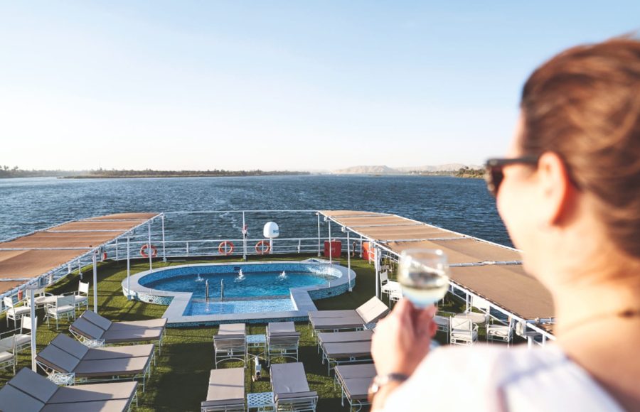 A woman enjoying a drink by the pool on the sun deck of the Imperial Nile Cruise.