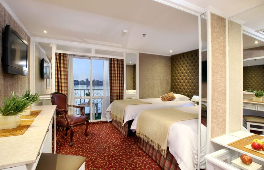 The elegant twin-bed cabin on the La Traviata Nile Cruise featuring a private balcony view.