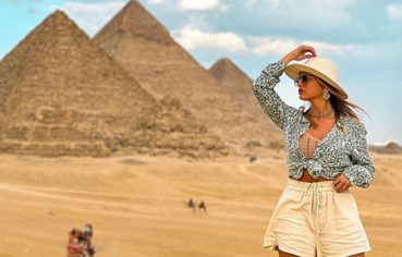A woman wearing a sun hat posing in front of the Giza Pyramids during a last-minute Egypt tour 9 days