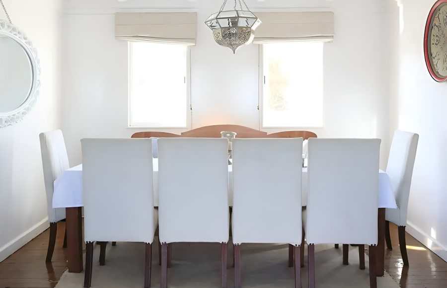 Elegant indoor dining area with a long table and white upholstered chairs