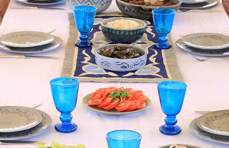 Close-up of a set dining table with blue glassware and Egyptian dishes.