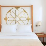 Luxury cabin bedroom with a gold geometric headboard and white linens.