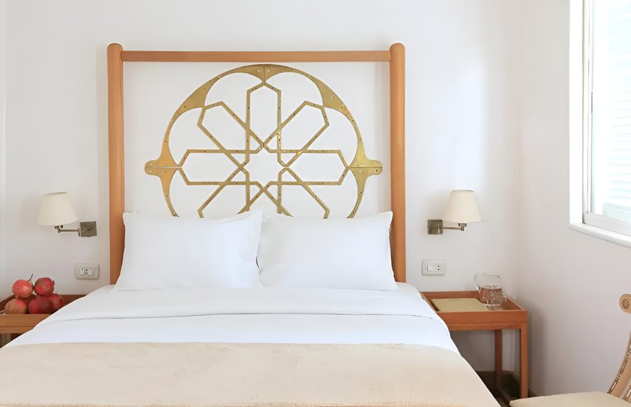 Luxury cabin bedroom with a gold geometric headboard and white linens.