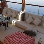 Outdoor sun deck lounge with white cushions and a pink striped ottoman.
