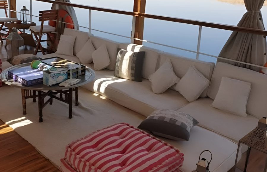 Outdoor sun deck lounge with white cushions and a pink striped ottoman.