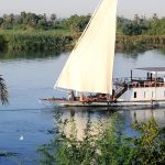 The Lazuli Dahabiya sailing past a small fishing boat on the Nile.