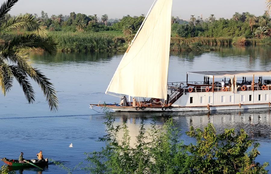 The Lazuli Dahabiya sailing past a small fishing boat on the Nile.