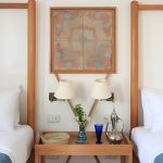 Close-up of two twin beds with white linens and a wooden nightstand featuring Egyptian decor.