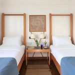 Wide shot of a twin cabin with blue bed runners and a central decorative nightstand.