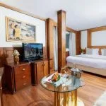 Ship's main atrium lounge with luxurious chandelier, marble floors, and leather seating.