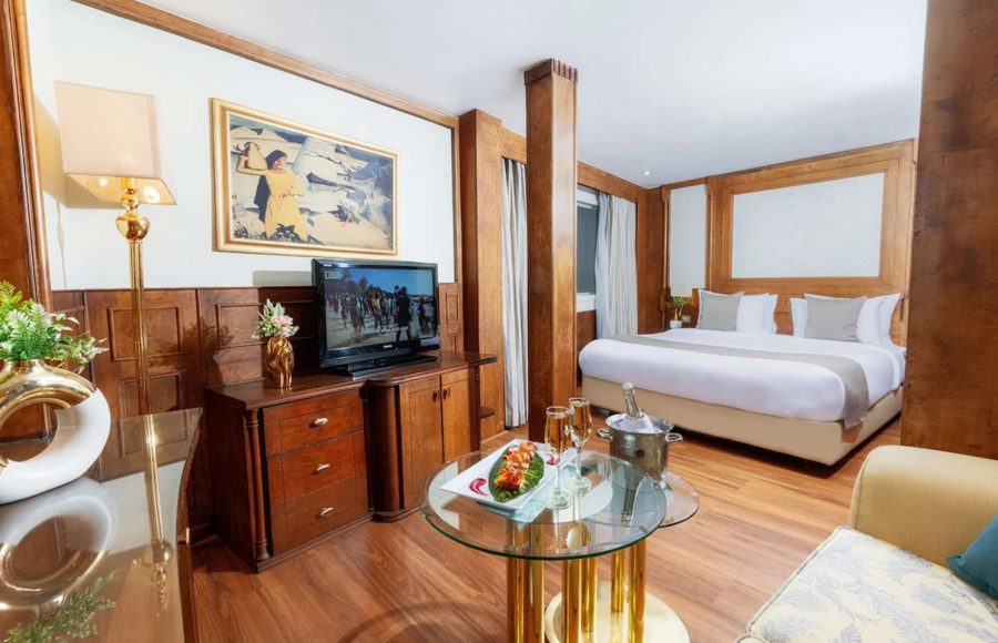 Ship's main atrium lounge with luxurious chandelier, marble floors, and leather seating.