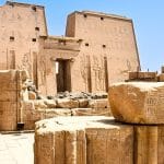 Exterior ruins and pylon of Edfu Temple against a blue sky.