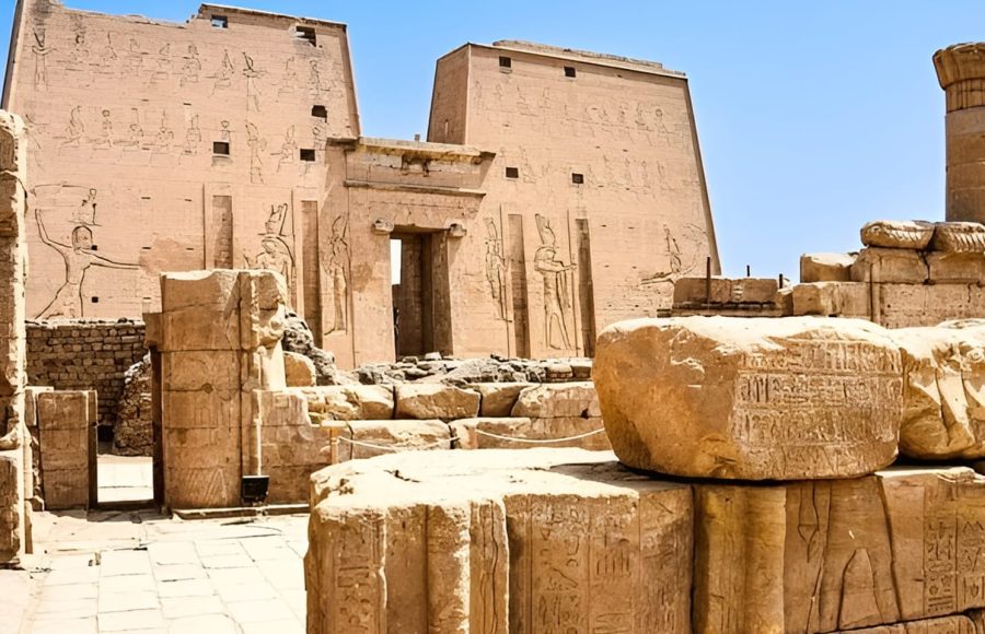 Exterior ruins and pylon of Edfu Temple against a blue sky.