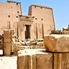 Exterior ruins and pylon of Edfu Temple against a blue sky.