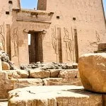 Exterior ruins and pylon of Edfu Temple against a blue sky.