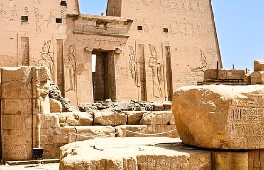 Exterior ruins and pylon of Edfu Temple against a blue sky.