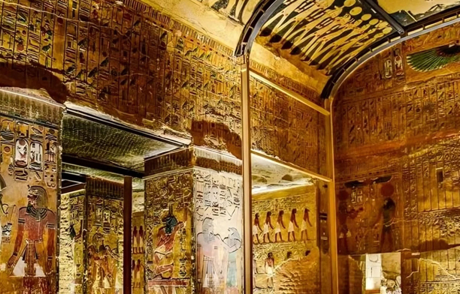 Interior view of an ancient Egyptian tomb with gold-colored walls and hieroglyphs