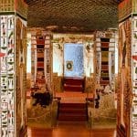 Interior view of an ancient Egyptian tomb with painted pillars and walls