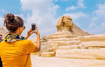 A tourist taking a photo of the Great Sphinx of Giza during a luxury Cairo Nile cruise Hurghada 12 days tour package.