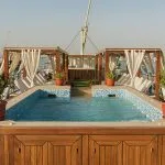 Close-up of a wooden-framed swimming pool on a boat deck during the day.