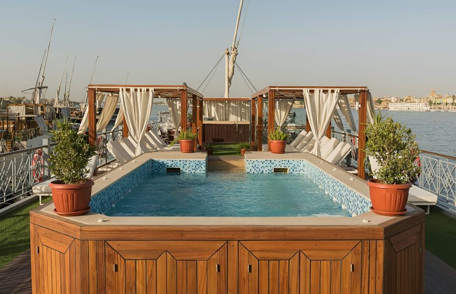 Close-up of a wooden-framed swimming pool on a boat deck during the day.