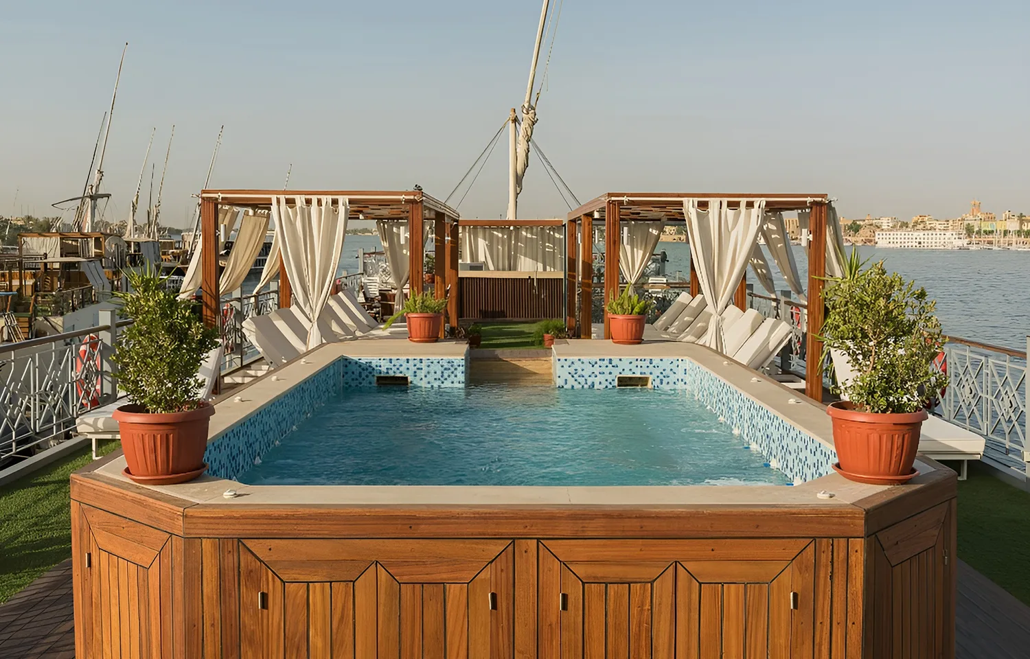 Close-up of a wooden-framed swimming pool on a boat deck during the day.