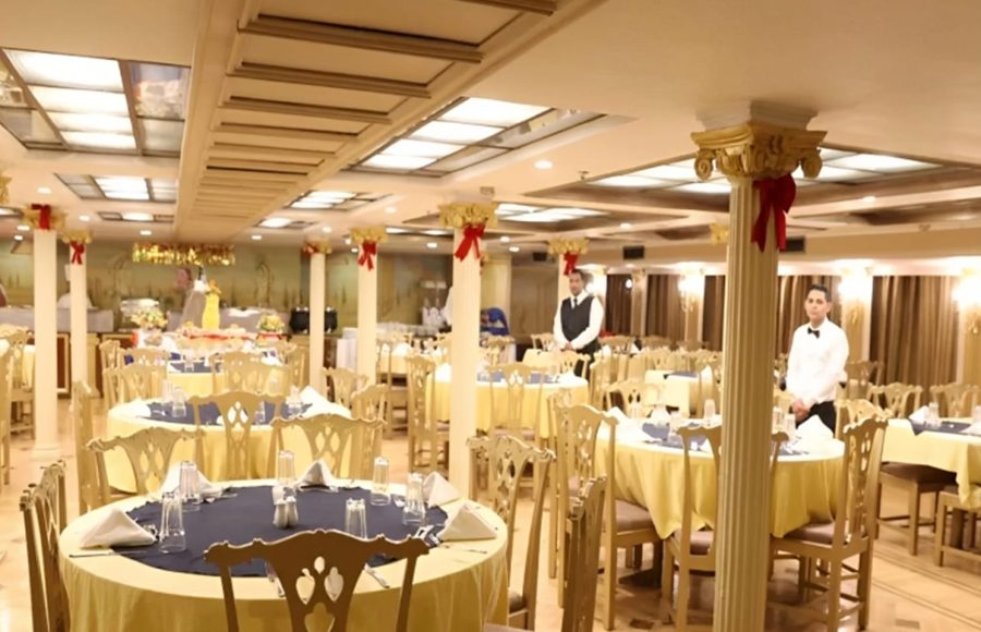 Formal restaurant with round tables and white-clad staff.