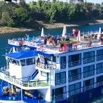 Exterior side view of the MS Al Nabilatan Nile Cruise ship sailing past lush riverbanks.