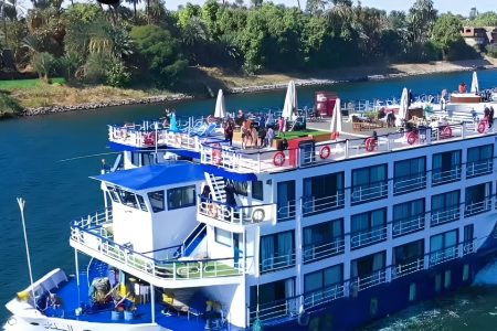 Exterior Side View Of The Ms Al Nabilatan Nile Cruise Ship Sailing Past Lush Riverbanks.