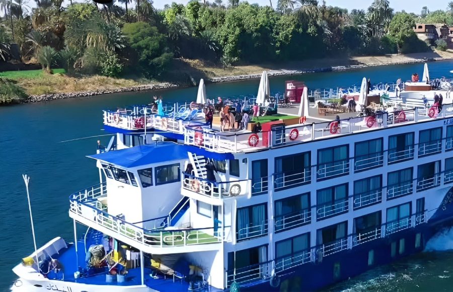 Exterior side view of the MS Al Nabilatan Nile Cruise ship sailing past lush riverbanks.