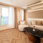 The elegant living area of the presidential suite on the MS Alma Nile Cruise, featuring a modern sofa, a stylish coffee table, and a large window with panoramic views of the river.