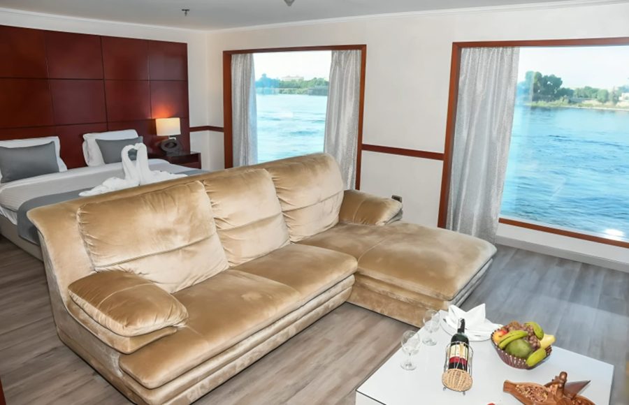 Modern cruise suite with a large sofa and floor-to-ceiling windows.
